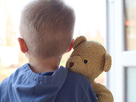 Ein kleiner Junge hält seinen Teddybär im Arm.